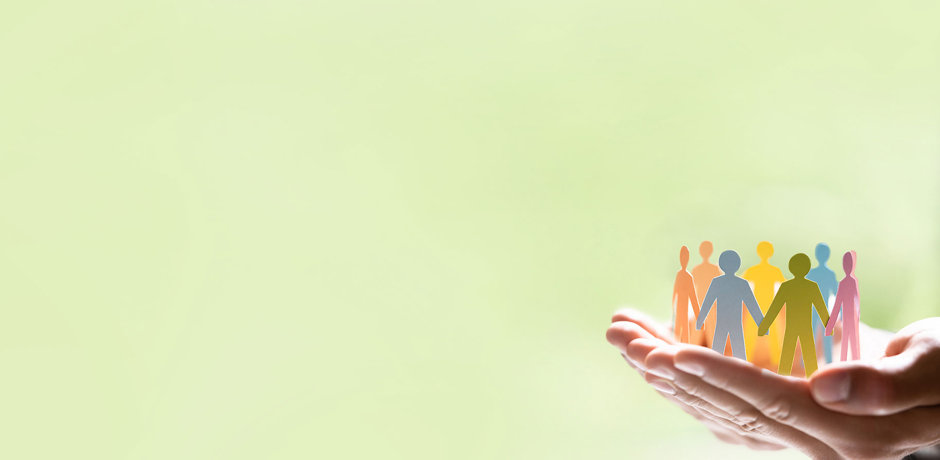 A hand holds colourful paper silhouettes of people, symbolising community and support.