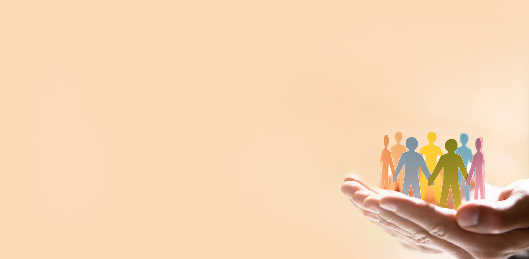 Hands hold a group of colourful paper figures arranged holding hands, set against a light background.